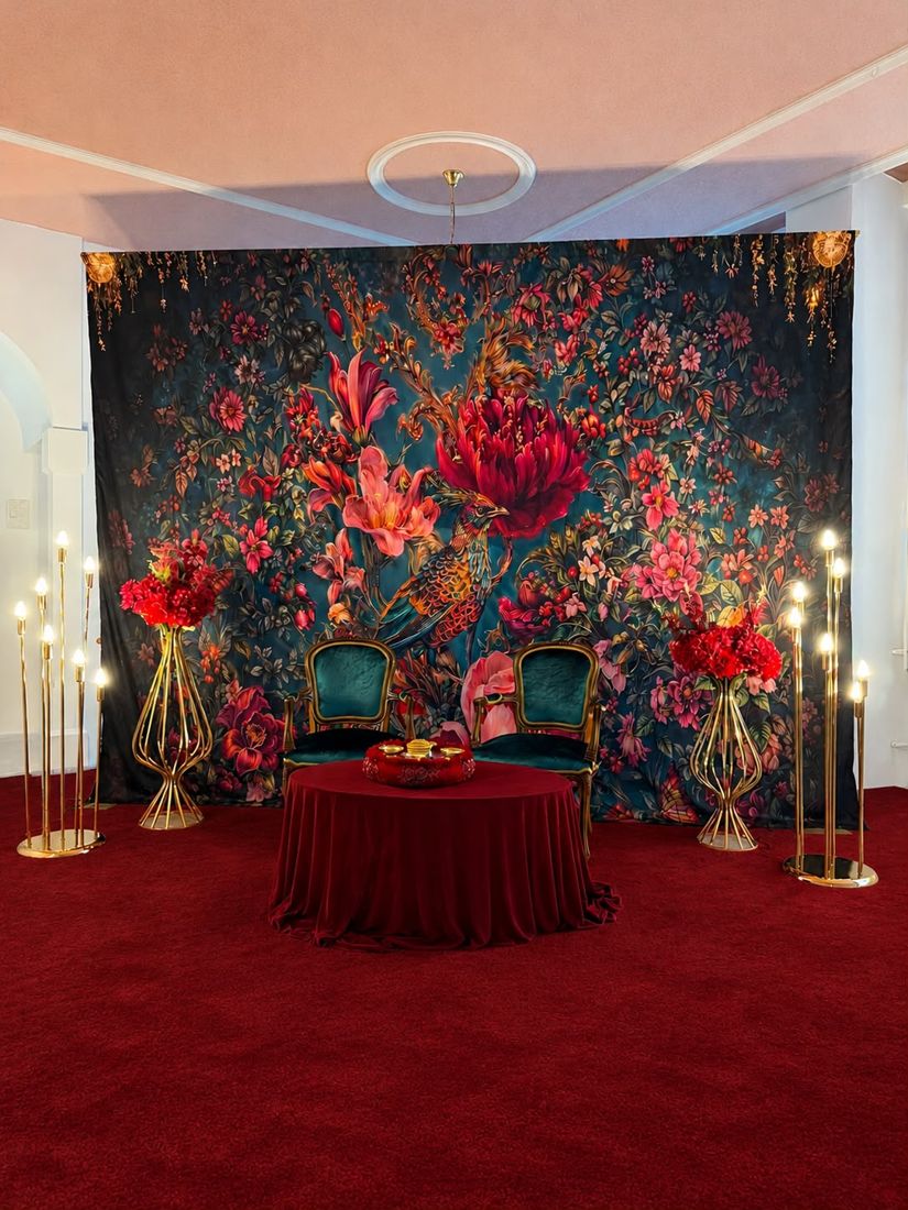 Blumen-Rückwand mit grünen Samtstühlen und rotem Tisch